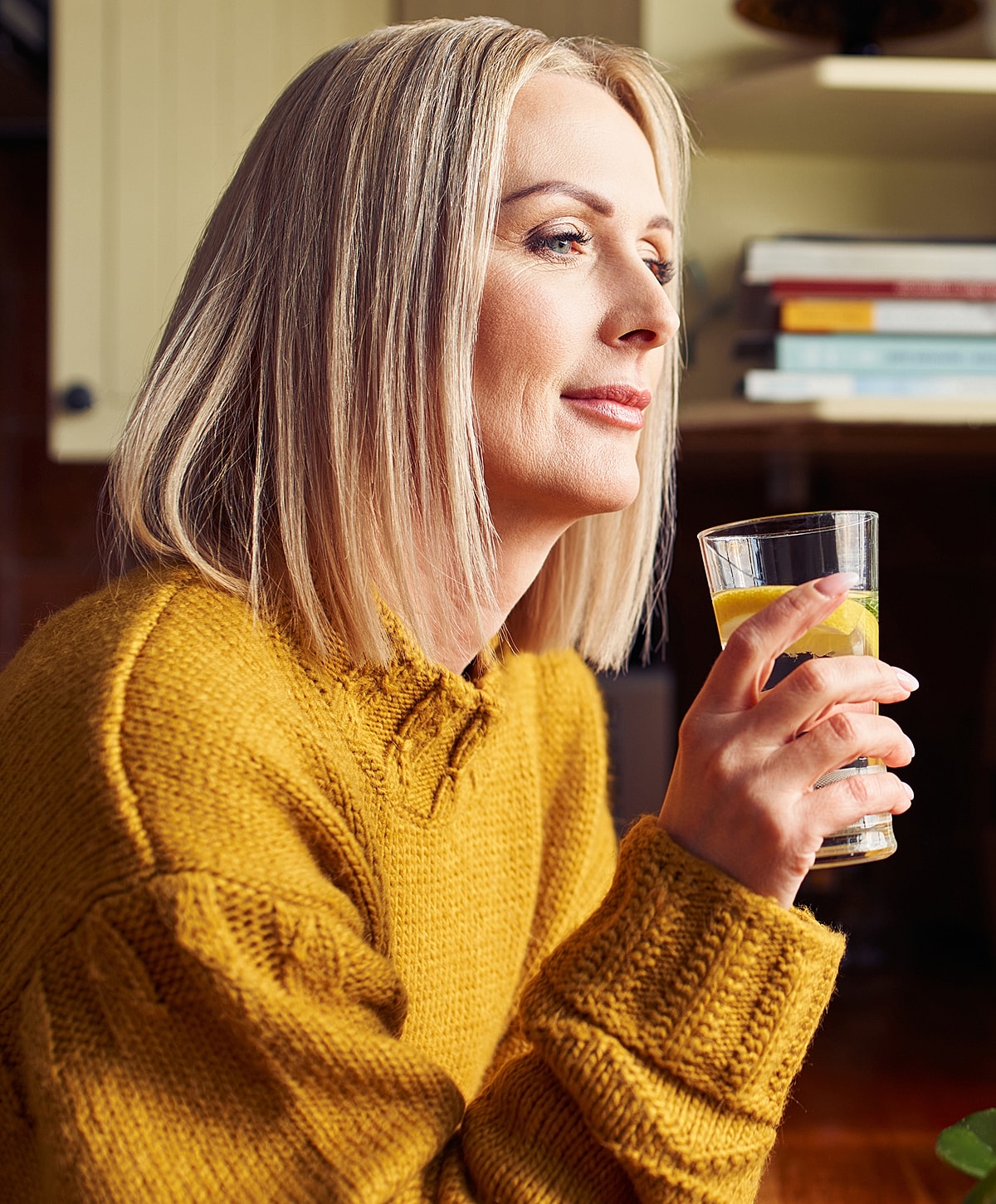 NYC Inguinal Hernia Surgery woman in yellow sweater holding a drink.