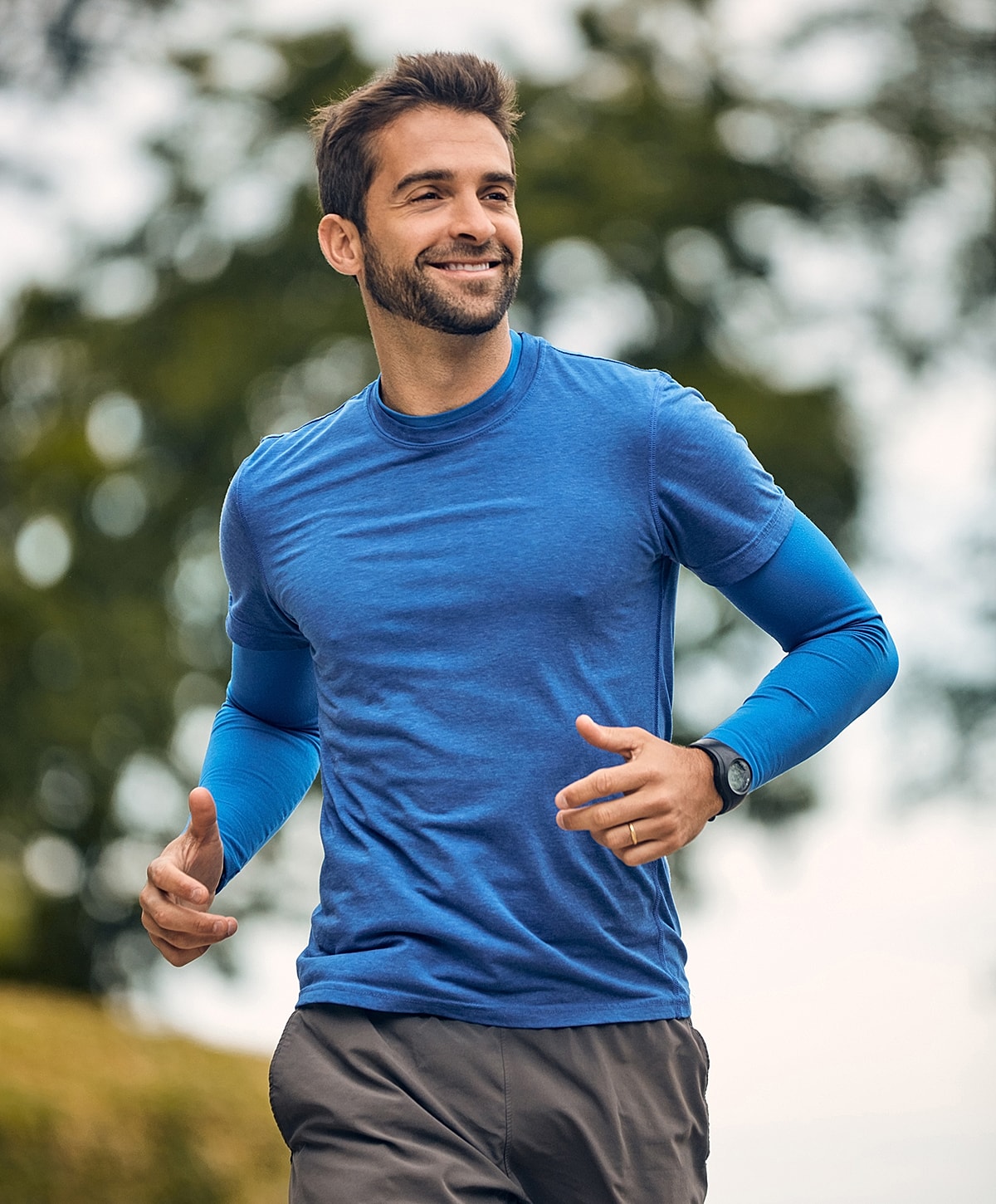 Smiling NYC Inguinal Hernia Surgery man jogging in blue athletic wear.