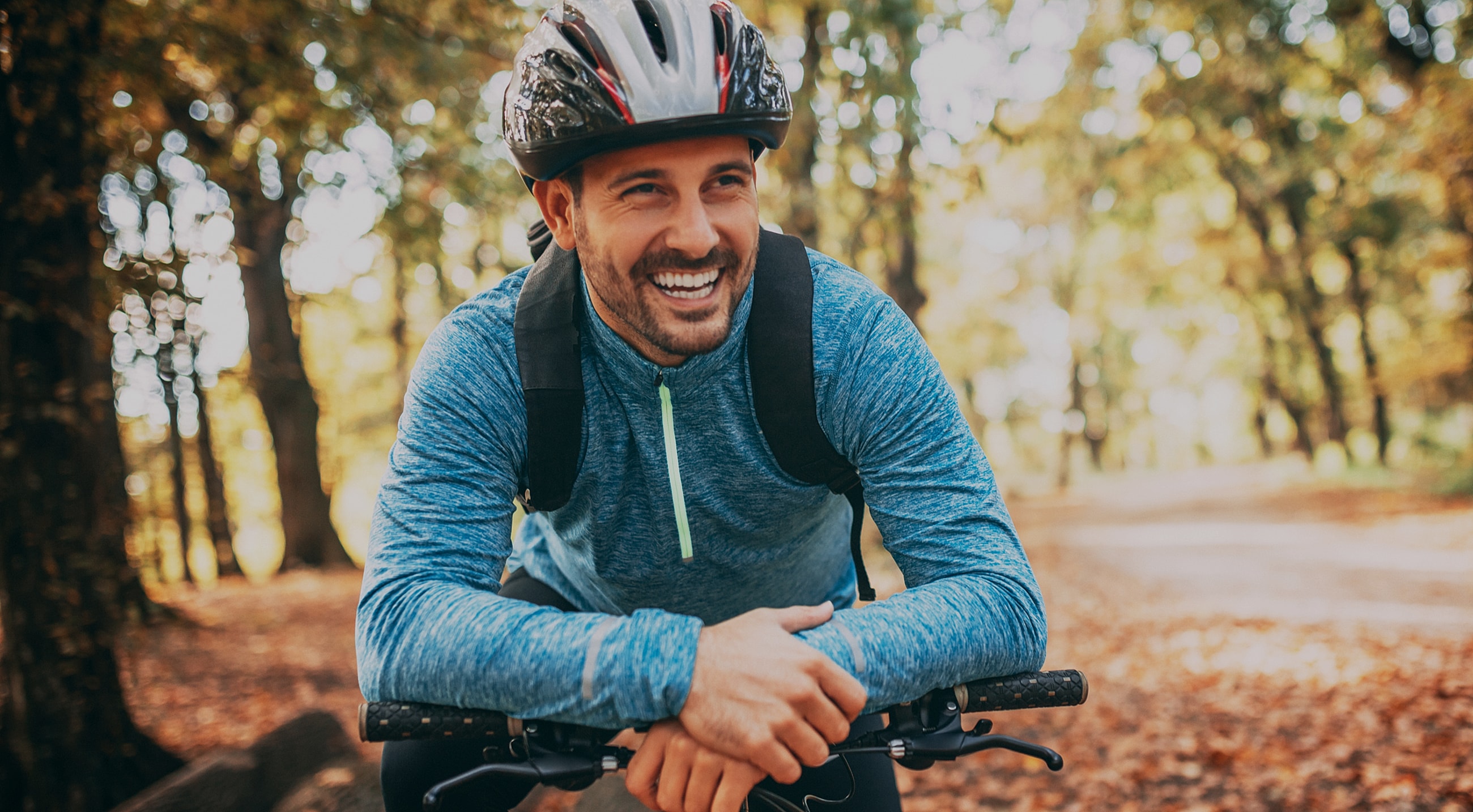 NYC minimally invasive surgery model in helmet biking through autumn forest.